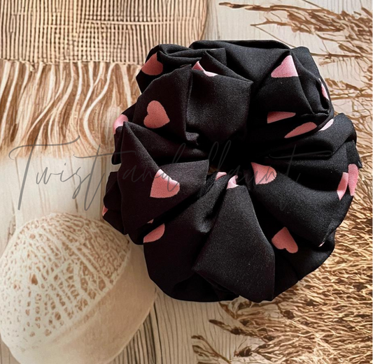 Black scrunchie with pink hearts on a textured surface