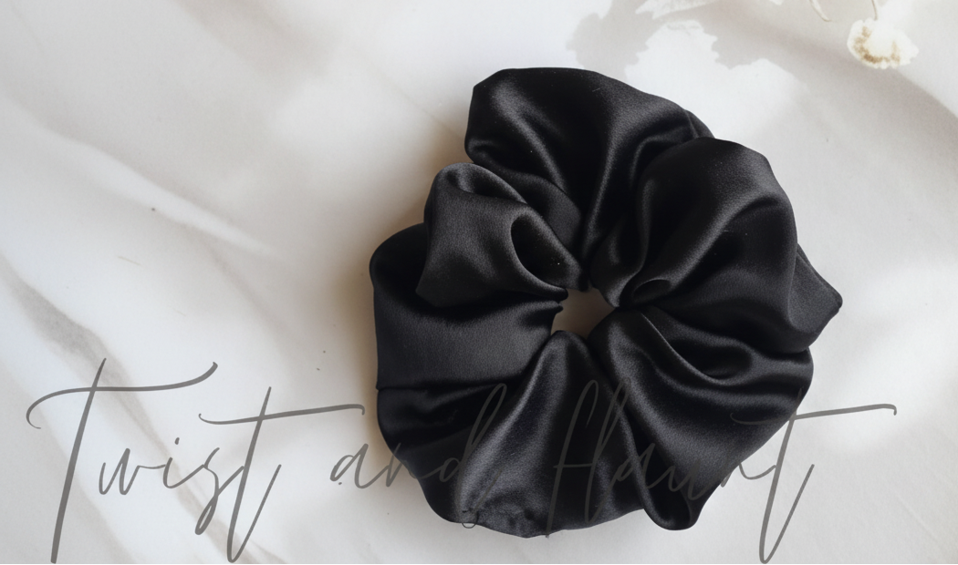 Black scrunchie on a white fabric background with floral elements