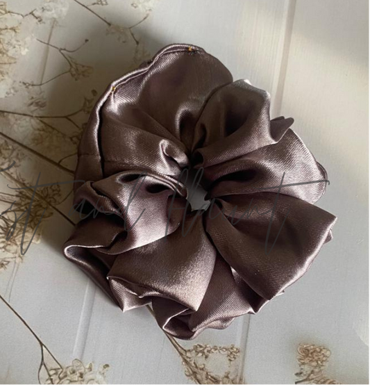Brown satin scrunchie on a light wooden surface with dried flowers