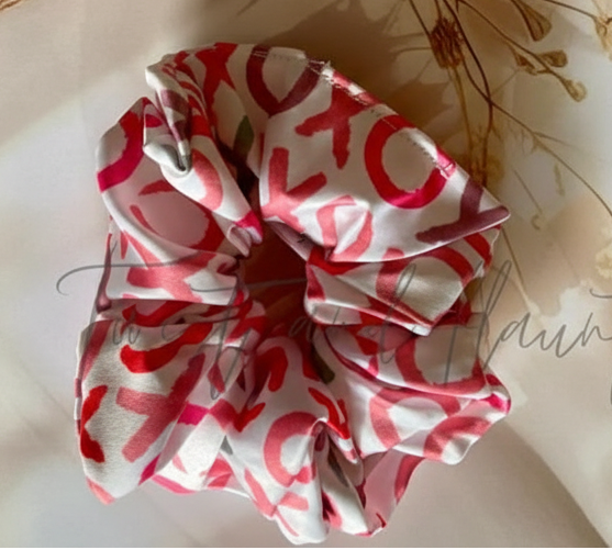 Red and white patterned scrunchie on a light surface with dried flowers and twigs.