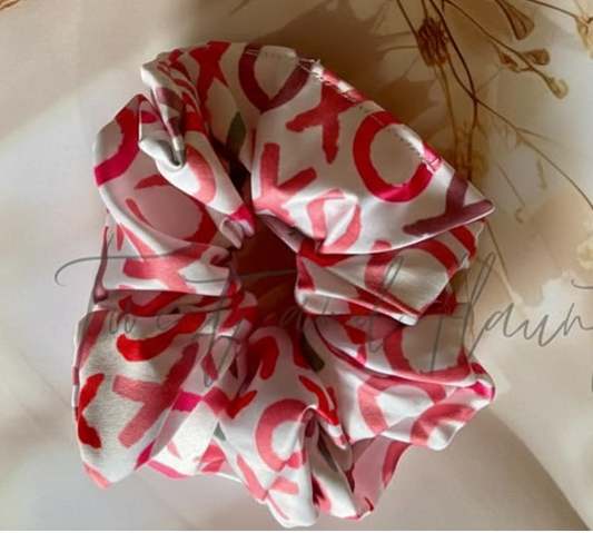 Red and white patterned scrunchie on a light surface with dried flowers and twigs.